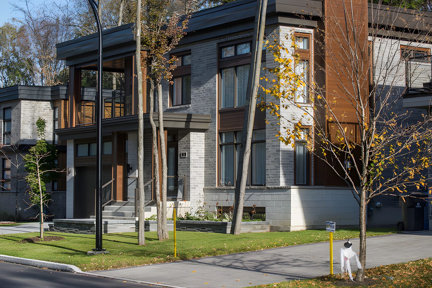 Une rue du Quartier Chambéry à Blainville : maisons contemporaines en pierre grise et en bois, à l'automne