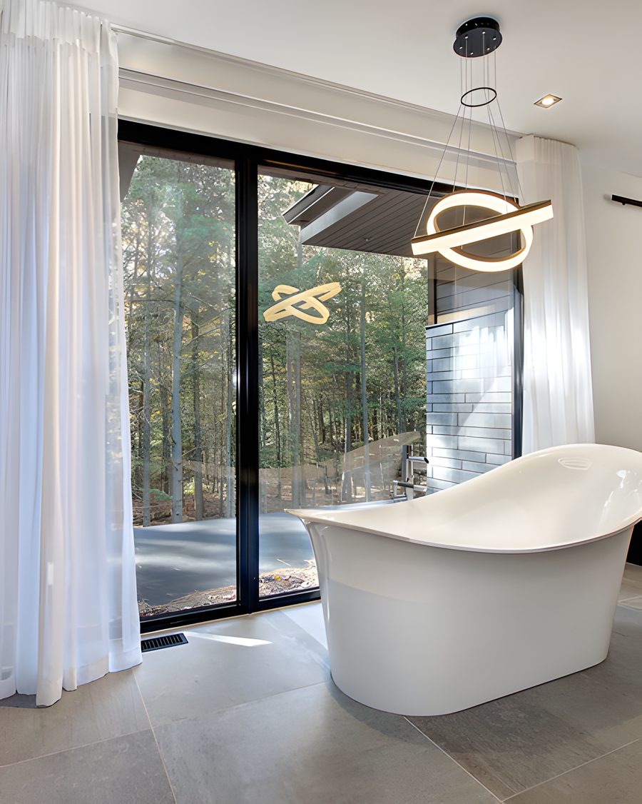 La salle de bain : baignoire autoportante devant une fenêtre, foyer vitré, luminaire suspendu